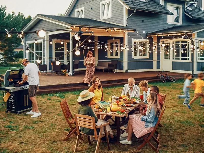 Family gathered around summer BBQ with wooden furniture