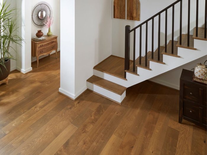 Warm hardwood flooring in an open entry way with stairs